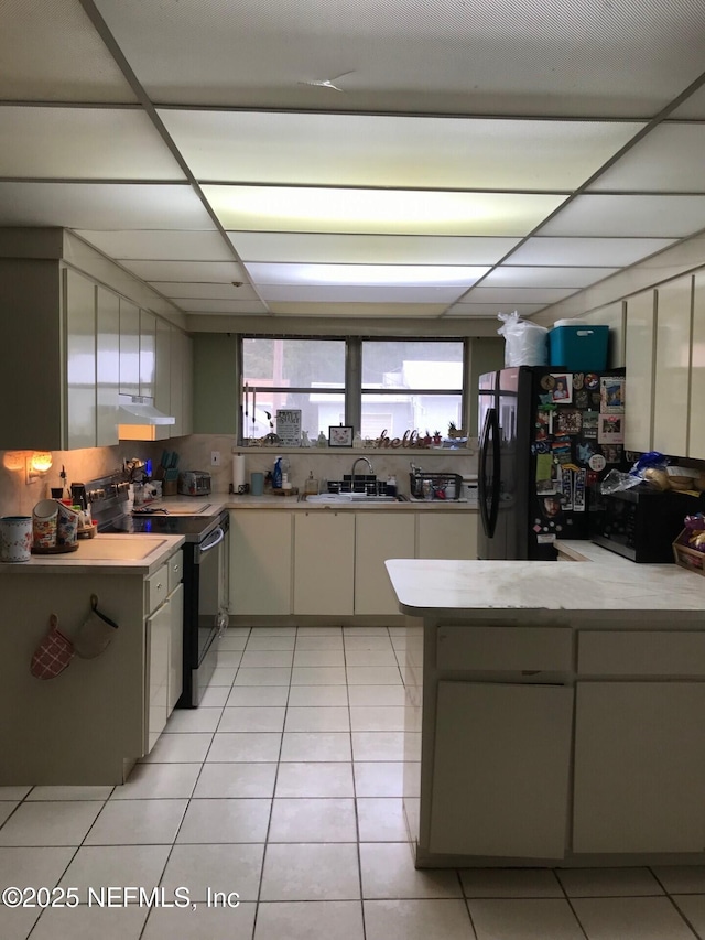 kitchen featuring black fridge, sink, electric range, light tile patterned floors, and kitchen peninsula