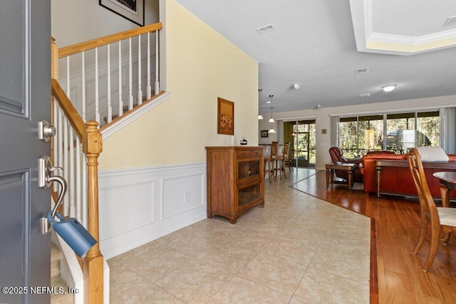 tiled entrance foyer featuring ornamental molding and a raised ceiling