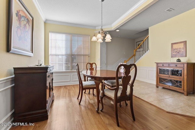 dining room with light wood-type flooring, crown molding, and a chandelier