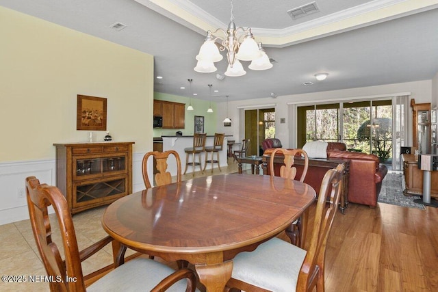 dining space featuring light wood-type flooring, an inviting chandelier, and crown molding