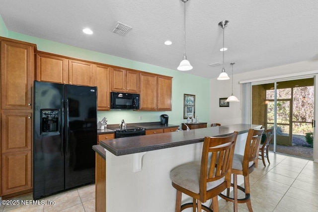 kitchen with pendant lighting, black appliances, a kitchen island, a kitchen bar, and light tile patterned flooring