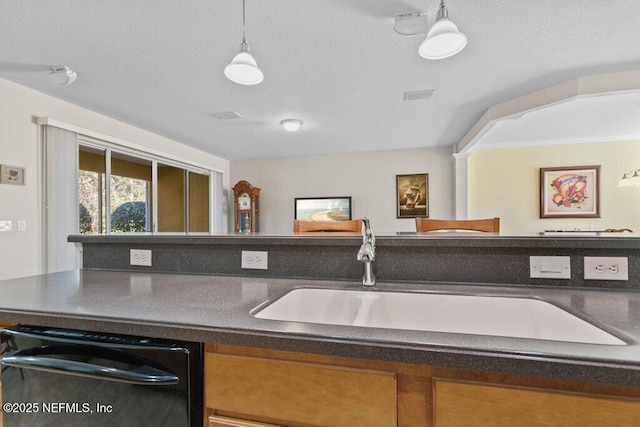 kitchen featuring decorative light fixtures, sink, a textured ceiling, and dishwasher