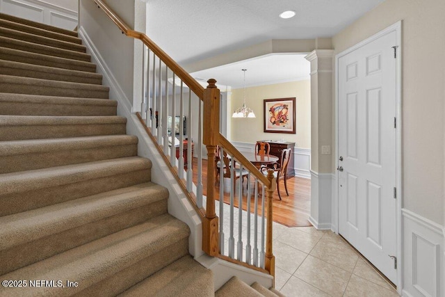 stairway with an inviting chandelier and tile patterned flooring