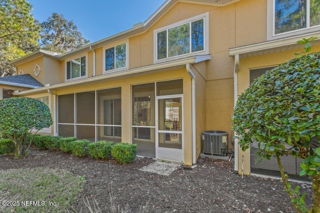 rear view of house featuring central air condition unit and a sunroom