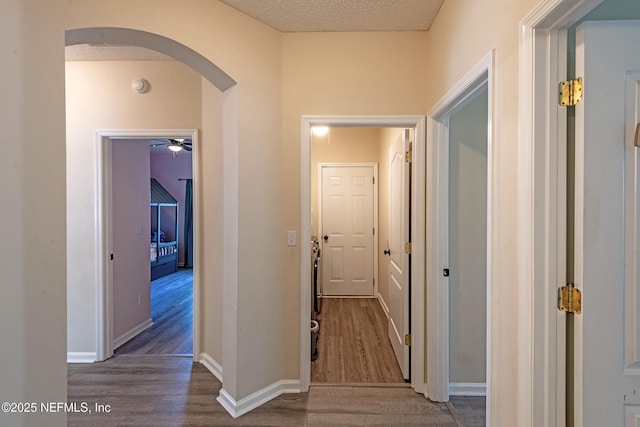 corridor with a textured ceiling and dark wood-type flooring