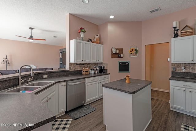 kitchen featuring sink, dark wood-type flooring, a kitchen island, stainless steel dishwasher, and white cabinets