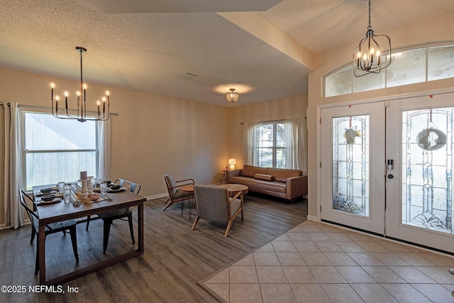 foyer entrance with tile patterned flooring, french doors, a textured ceiling, and a notable chandelier