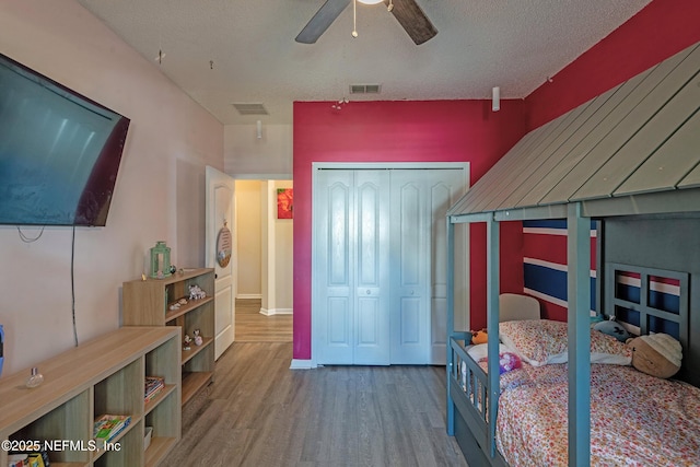 bedroom with hardwood / wood-style flooring, ceiling fan, a textured ceiling, and a closet