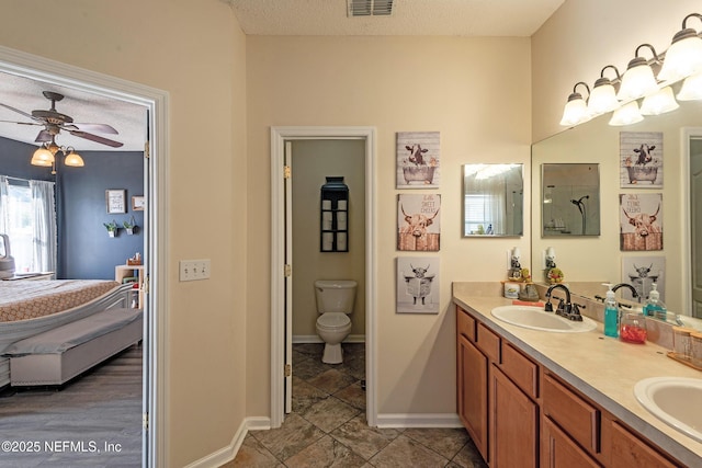 bathroom with ceiling fan, vanity, a textured ceiling, and toilet