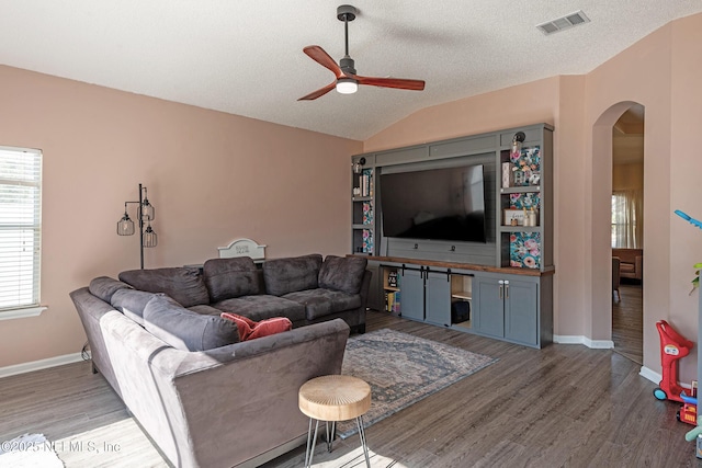 living room with a textured ceiling, hardwood / wood-style flooring, ceiling fan, and lofted ceiling