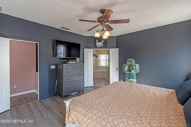 bedroom with ensuite bath, ceiling fan, hardwood / wood-style floors, and a textured ceiling