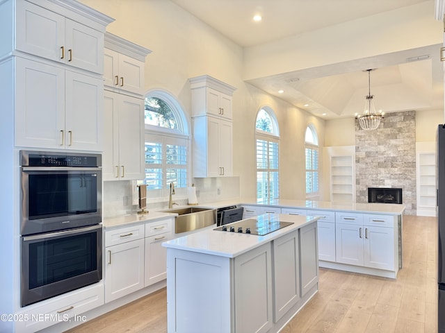 kitchen with kitchen peninsula, decorative backsplash, black appliances, a fireplace, and white cabinetry