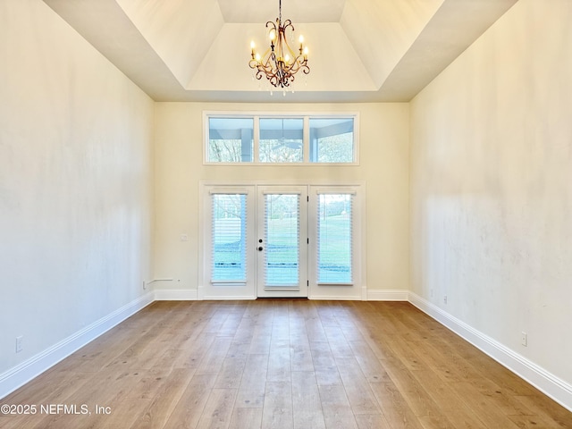 doorway to outside featuring a high ceiling, french doors, an inviting chandelier, and light hardwood / wood-style flooring