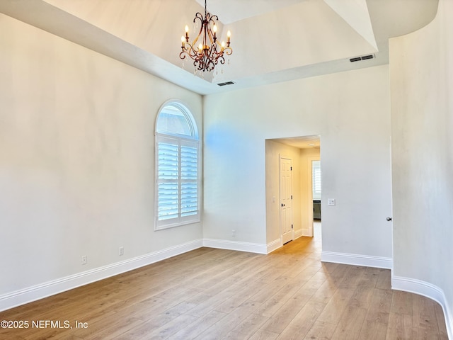 empty room with light hardwood / wood-style flooring and a notable chandelier