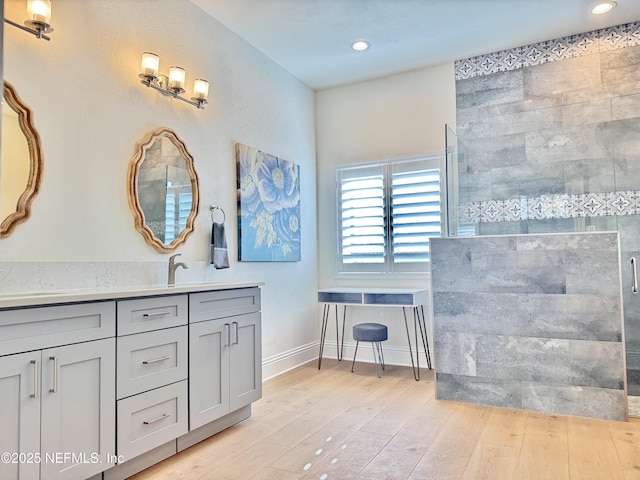 bathroom with wood-type flooring, a shower with shower door, and vanity