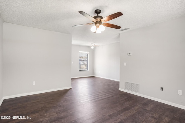 spare room with a textured ceiling, dark wood-style floors, visible vents, and baseboards