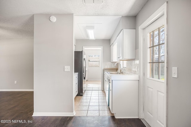 kitchen with light countertops, white cabinetry, a sink, and appliances with stainless steel finishes