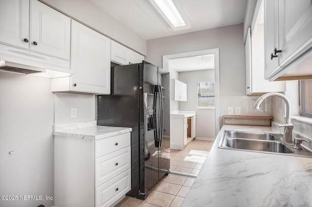 kitchen featuring white cabinetry, light tile patterned floors, light countertops, and a sink