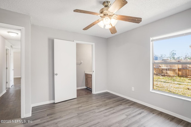 unfurnished bedroom with a textured ceiling, wood finished floors, and multiple windows