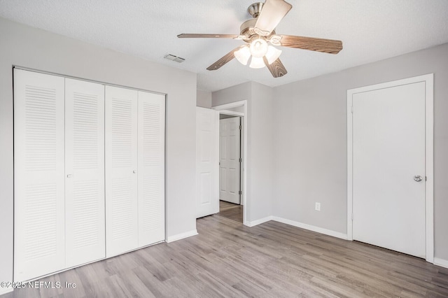 unfurnished bedroom featuring light wood-type flooring, visible vents, a closet, and baseboards