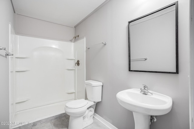 bathroom featuring baseboards, a sink, a shower, and toilet