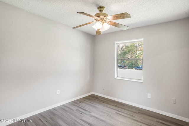 unfurnished room featuring baseboards, ceiling fan, wood finished floors, and a textured ceiling