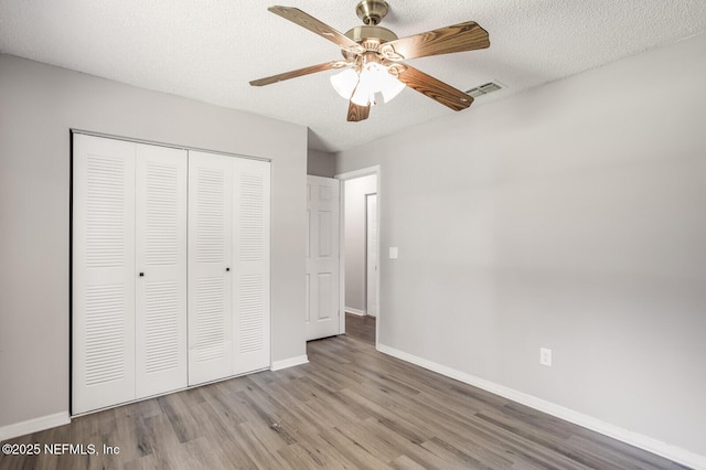 unfurnished bedroom featuring visible vents, light wood finished floors, baseboards, a textured ceiling, and a closet