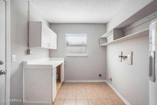 laundry area with cabinet space, baseboards, a textured ceiling, and light tile patterned floors