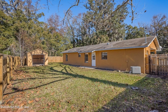 rear view of property with an outbuilding, a lawn, cooling unit, a storage unit, and a fenced backyard