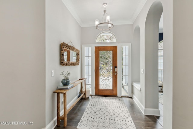 entryway with a notable chandelier, dark hardwood / wood-style floors, and ornamental molding