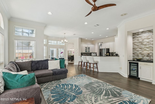 living room with ceiling fan with notable chandelier, dark hardwood / wood-style flooring, wine cooler, and crown molding