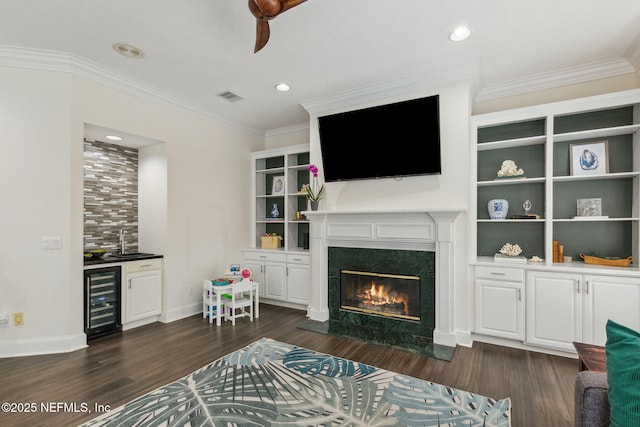 living room with a high end fireplace, dark hardwood / wood-style flooring, wine cooler, and ornamental molding