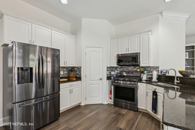 kitchen with stainless steel appliances, white cabinetry, dark stone counters, and sink