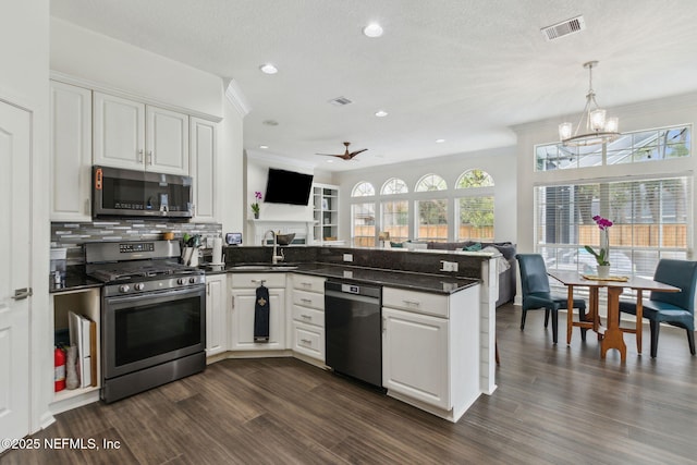 kitchen featuring kitchen peninsula, appliances with stainless steel finishes, ceiling fan with notable chandelier, sink, and white cabinetry