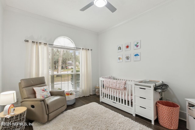 bedroom with crown molding, ceiling fan, dark hardwood / wood-style flooring, and a nursery area