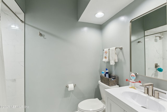 bathroom featuring tiled shower, vanity, and toilet