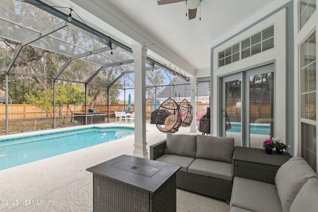 view of pool with an outdoor living space, a patio, glass enclosure, and ceiling fan