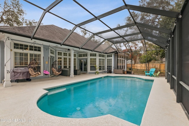 view of pool featuring glass enclosure, ceiling fan, a patio, and grilling area