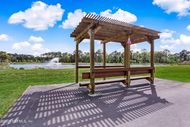 view of home's community with a water view, a pergola, and a yard