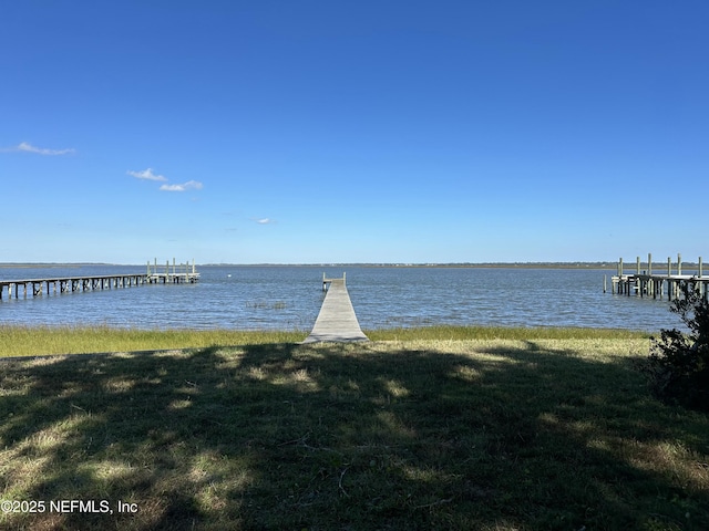 view of dock featuring a water view and a yard