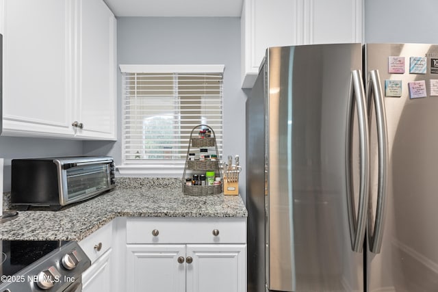 kitchen with stainless steel appliances, white cabinets, and light stone countertops