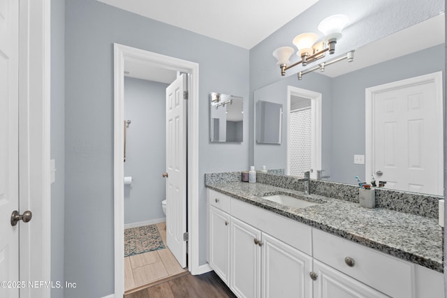 bathroom featuring toilet, wood-type flooring, vanity, and a notable chandelier