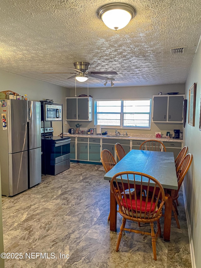 dining room with a textured ceiling, ceiling fan, and sink