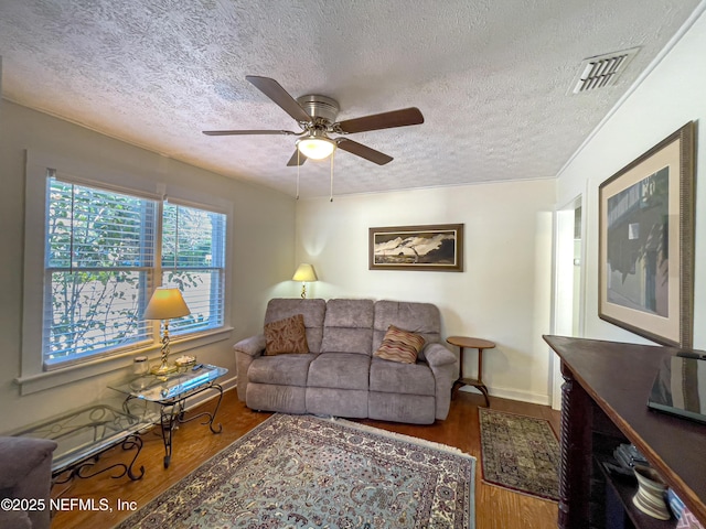 living room with ceiling fan, hardwood / wood-style floors, and a textured ceiling