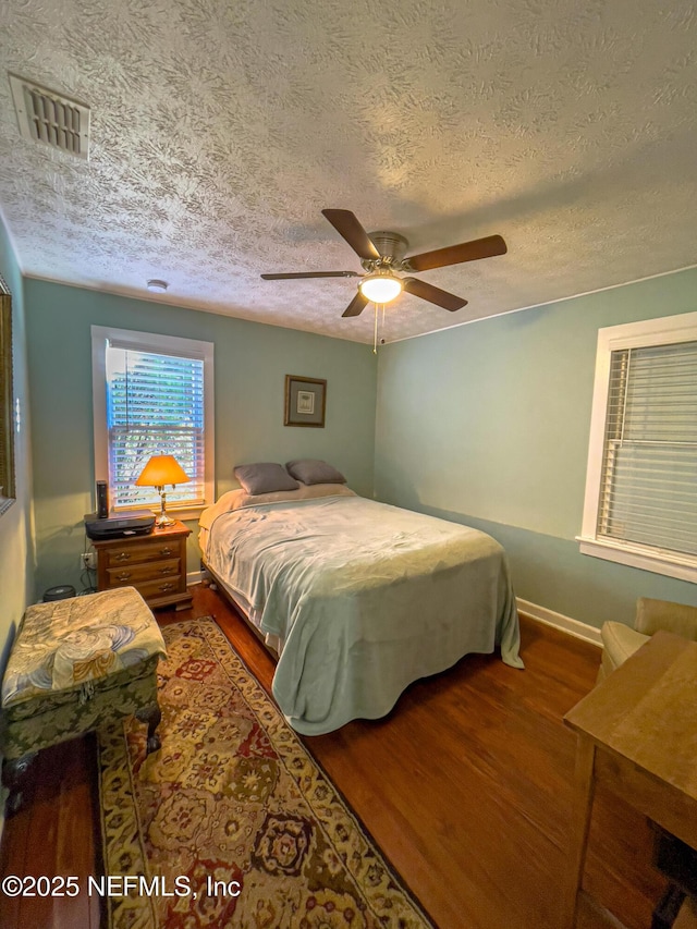 bedroom with ceiling fan, wood-type flooring, and a textured ceiling