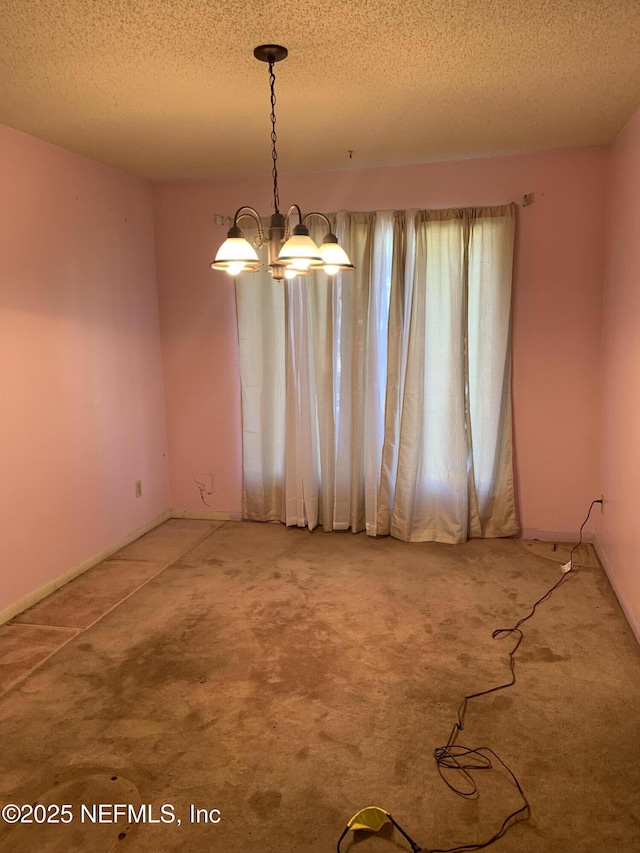 carpeted empty room with an inviting chandelier and a textured ceiling