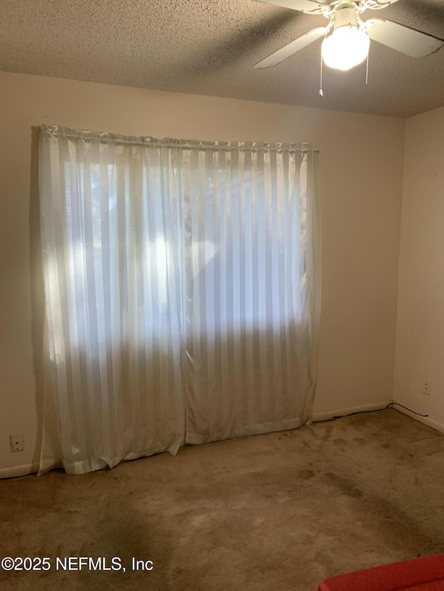 empty room featuring ceiling fan, a textured ceiling, and carpet