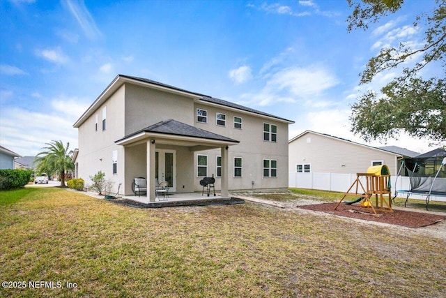 back of property featuring a trampoline, a playground, a patio, and a yard