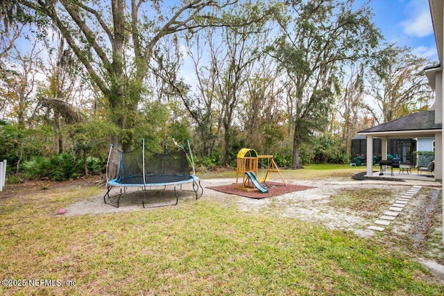 view of yard featuring a playground, a trampoline, and a patio