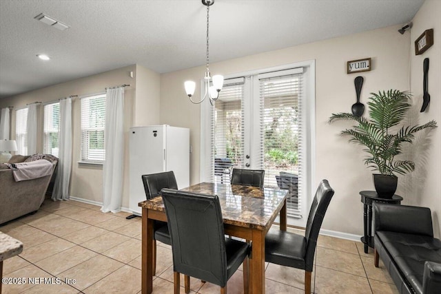 tiled dining area featuring a textured ceiling and a notable chandelier